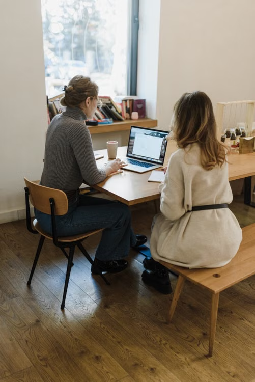 Two caregivers sitting at a table discussing strategies in front of a laptop