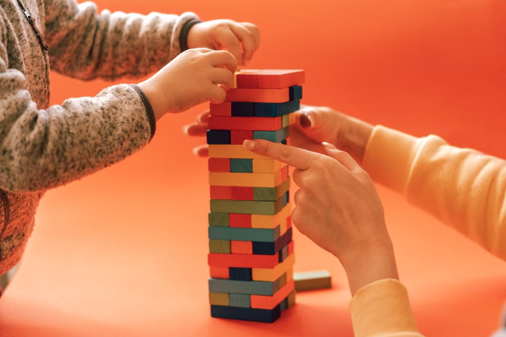 A child building a colorful wooden block tower with a therapist