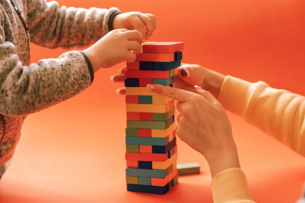 A child building a colorful wooden block tower with a therapist