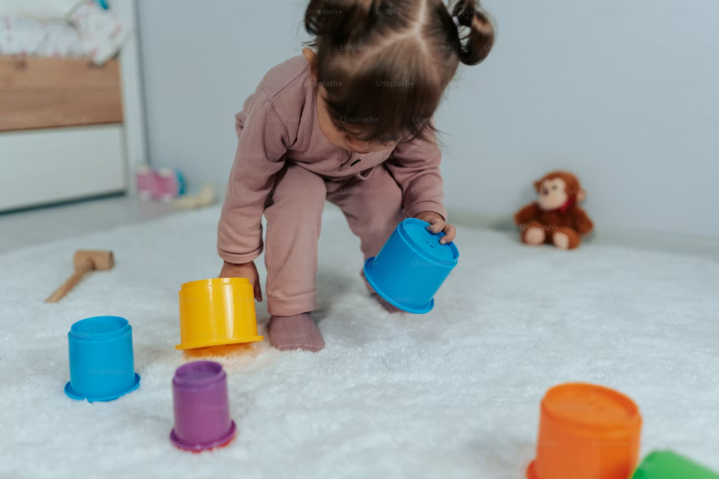 A child stacking colorful cups on a white rug